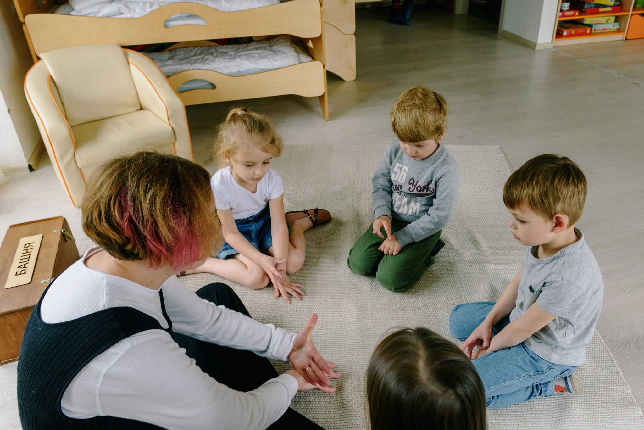 Group of children engaged in a learning activity, sitting in a circle on the classroom floor.